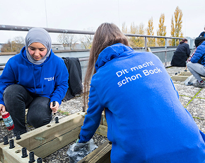 Auszubildende bei der Pflanzarbeit, Jacke mit Aufschrift „Dit macht schon Bock"