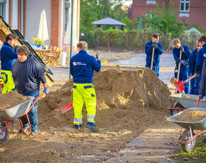 Gruppe von Auszubildenden beim Anlegen eines Grünbereichs an einem Berliner Ausbildungsstandort