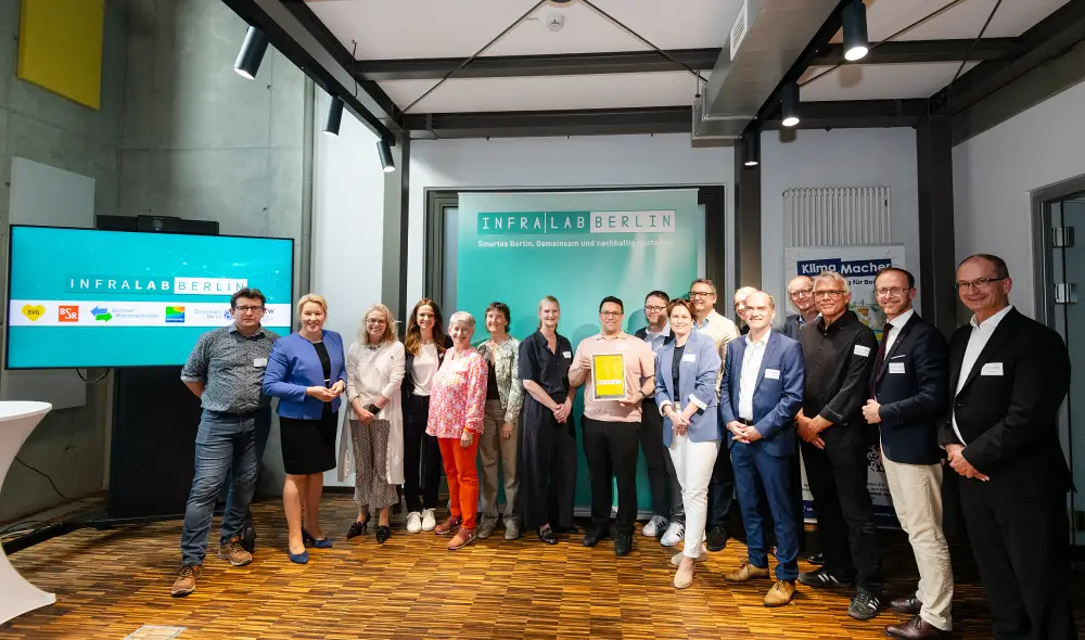 Gruppenfoto von Teilnehmenden einer InfraLab-Veranstaltung vor einer Präsentationswand